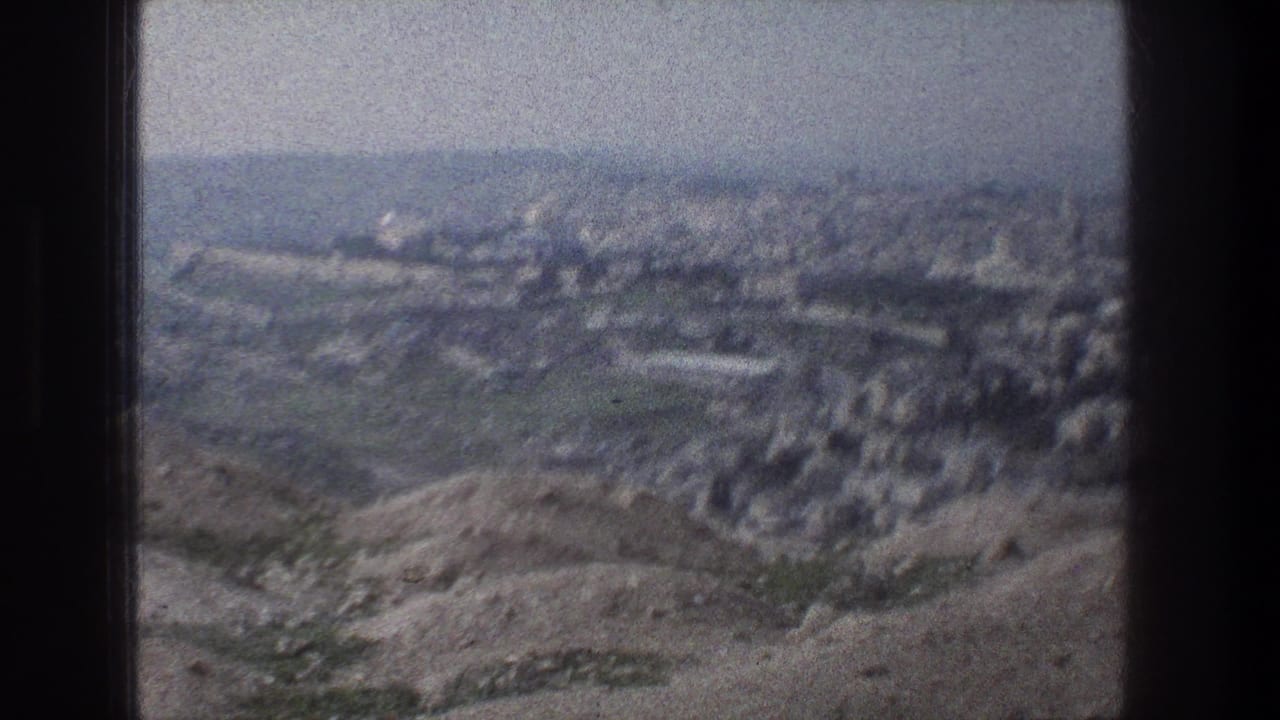 Jerusalem cityscape seen from above on 8mm film, with arid hills in front and pale urban blocks stretching across the valley.