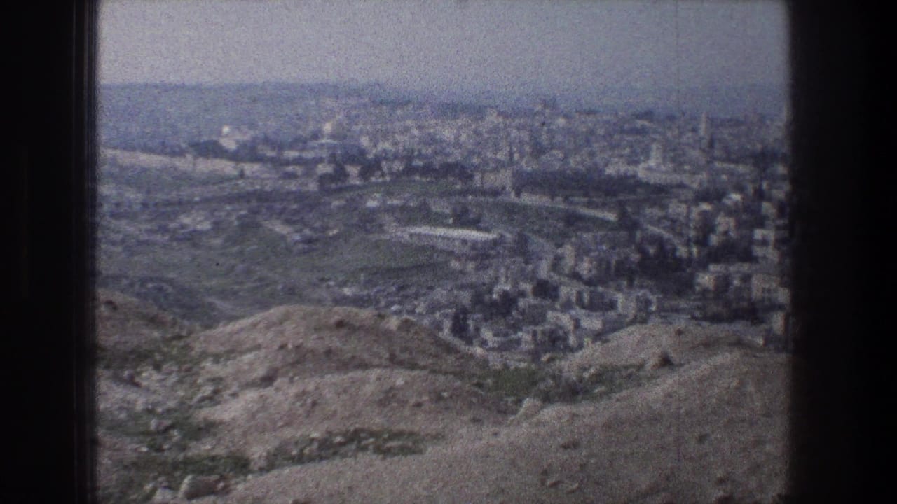 Panoramic city view beyond rolling hills with a pale hazy horizon.