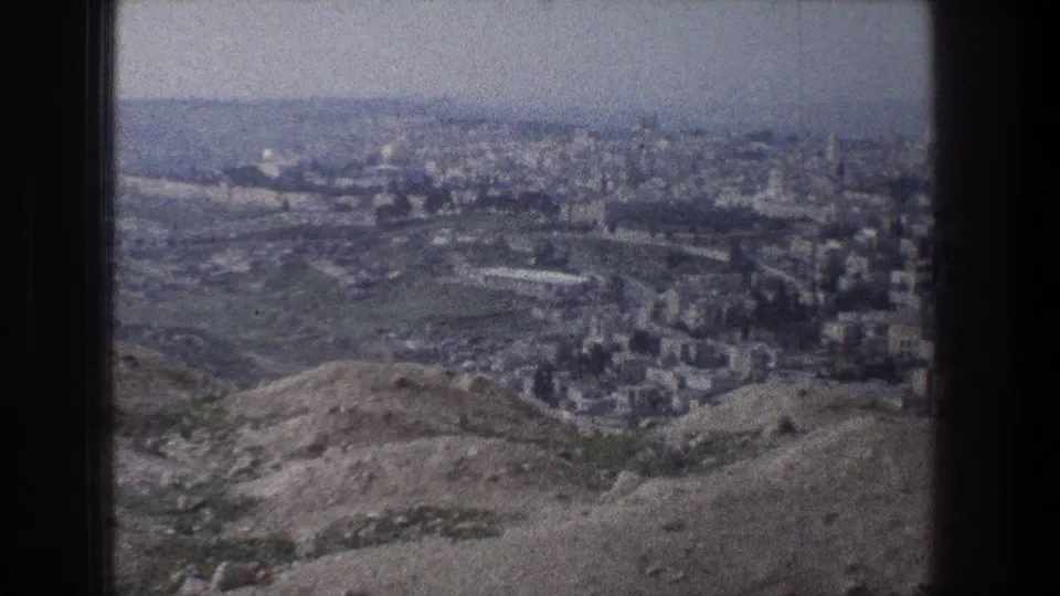 Jerusalem appears beyond rounded hills in this 1976 home-movie frame, with clustered buildings and a broad hazy skyline.