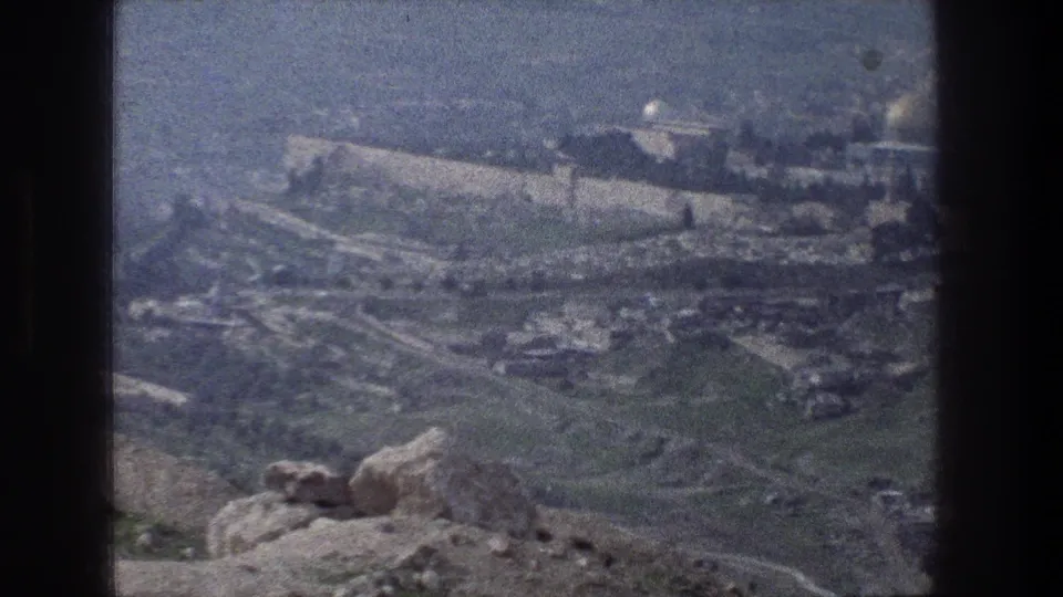 Late frame from the 1976 Jerusalem panorama, showing the stone wall line, rocky overlook, green slopes, and hazy distance.