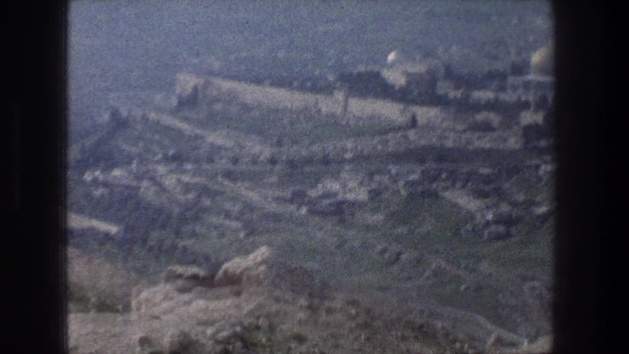 Elevated view over a rocky hillside village with fields and stone walls.