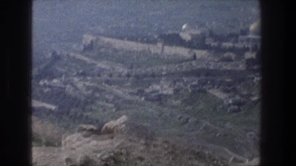1976 Jerusalem-area home-movie frame showing a soft, elevated view of rocky terrain, village structures, and hillside walls.