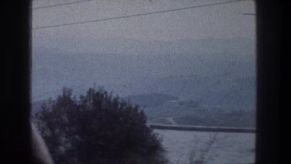 The final frame looks past a vehicle divider toward foreground trees and hazy hills around Jerusalem.