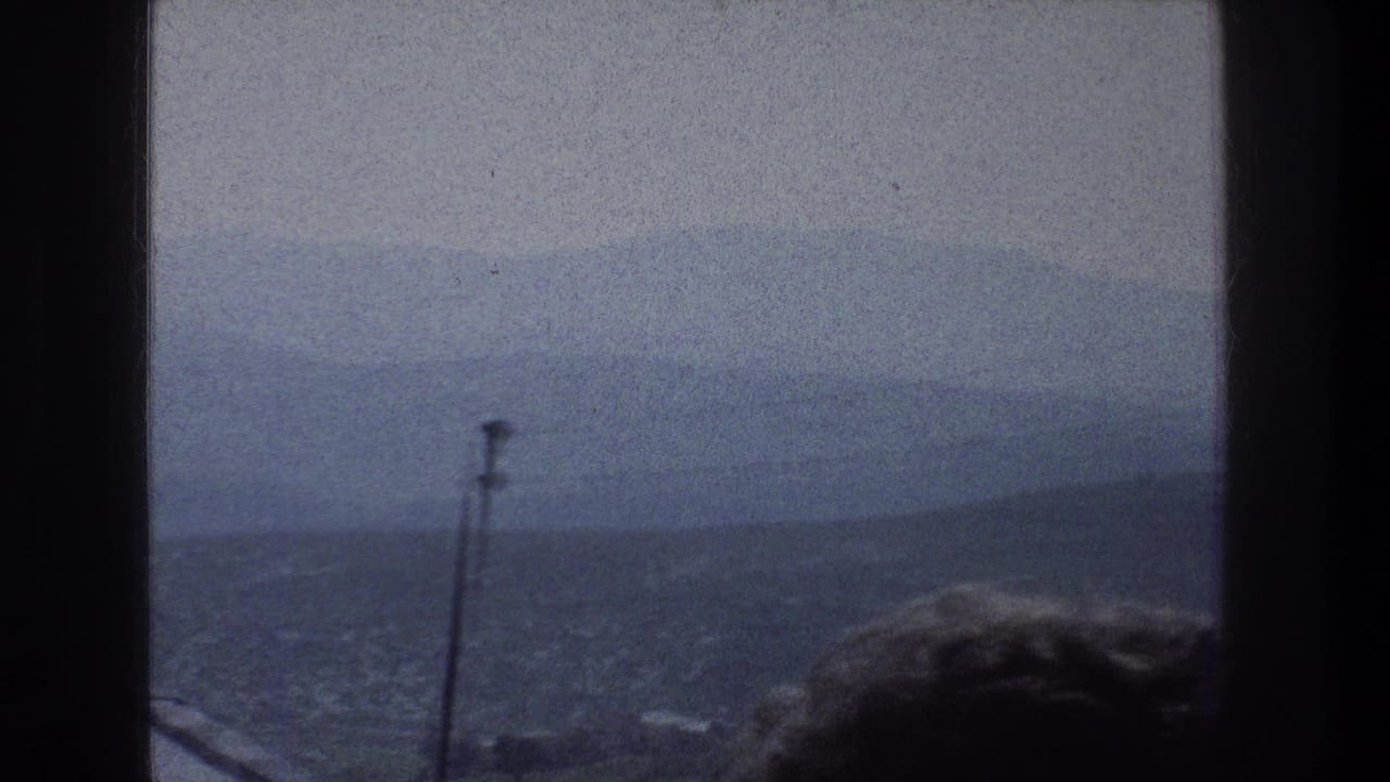 1976 8mm Jerusalem view through a window, showing haze over distant buildings and hills with a silhouetted head low in frame.