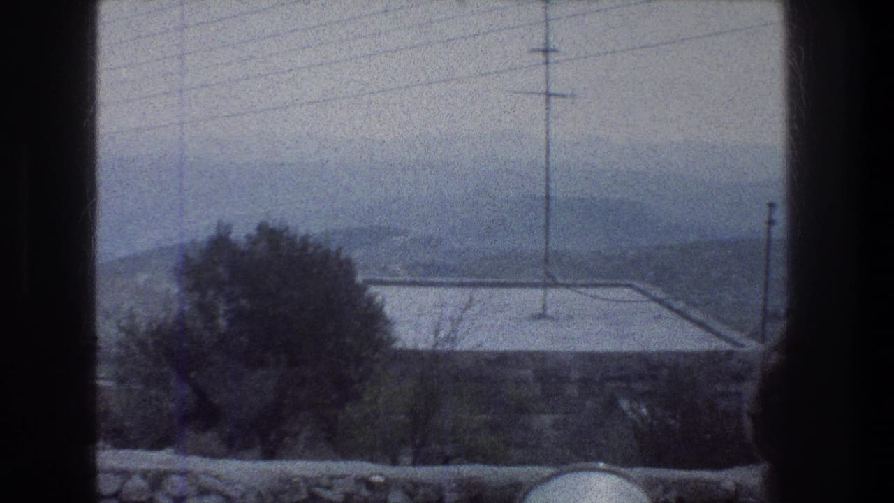 Window-framed view of a rooftop, utility pole, trees, and hazy hills beyond.