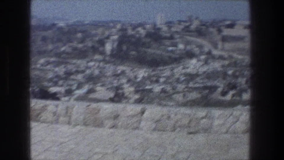 A handheld 8mm panorama shows stone walls and blurred city structures in Jerusalem during the stated 1976 trip.