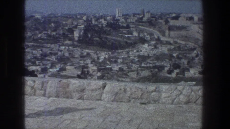 A wide Jerusalem city view shows rooftops, stone walls, and distant structures in faded 1970s 8mm color.