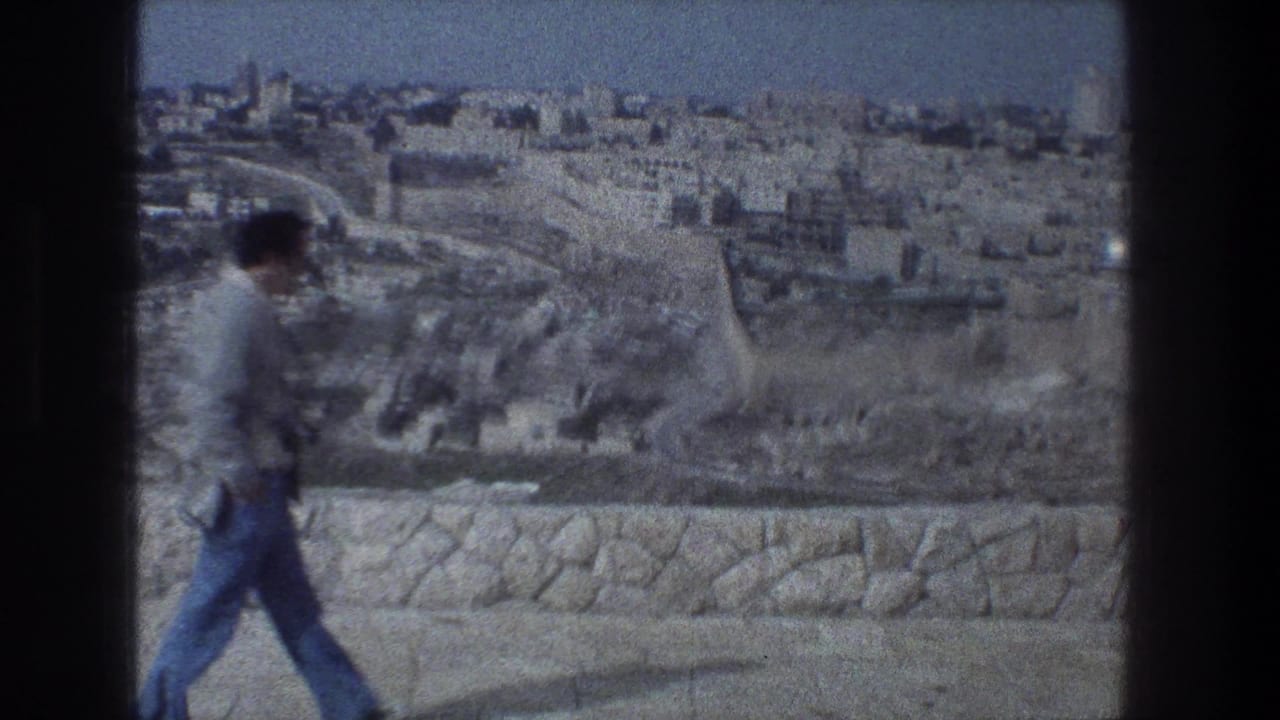 Man carrying a camera walks past a Jerusalem overlook.