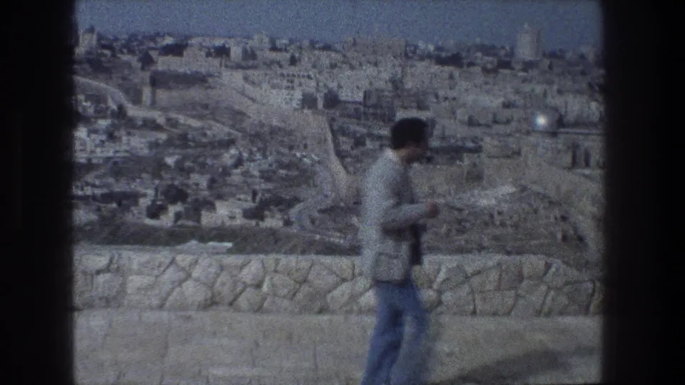 Visitor with a camera moves across the foreground of a 1976 Jerusalem overlook, partly obscuring the city view.