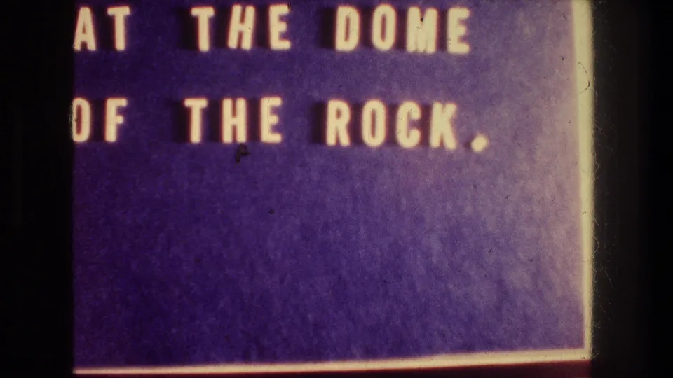 1976 8mm title card with cropped yellow lettering reading at the Dome of the Rock against a purple background.