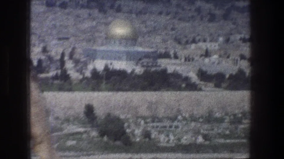 1976 Jerusalem 8mm view of a golden-domed structure, trees, stone buildings, and a pale foreground wall.