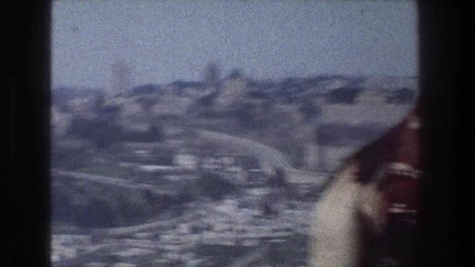 Soft, blurred 1976 Jerusalem frame with a hillside city view and the edge of the camel moving out of frame.