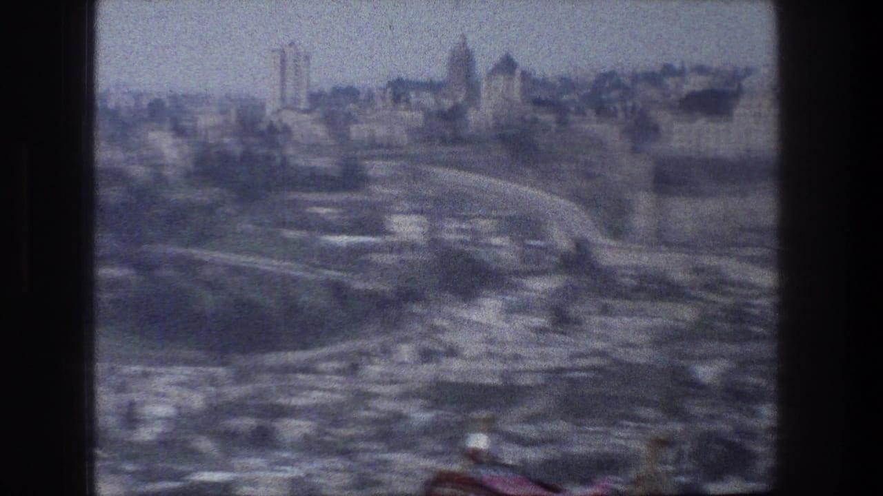 Aerial cityscape with roads, clustered buildings, and distant towers under haze.