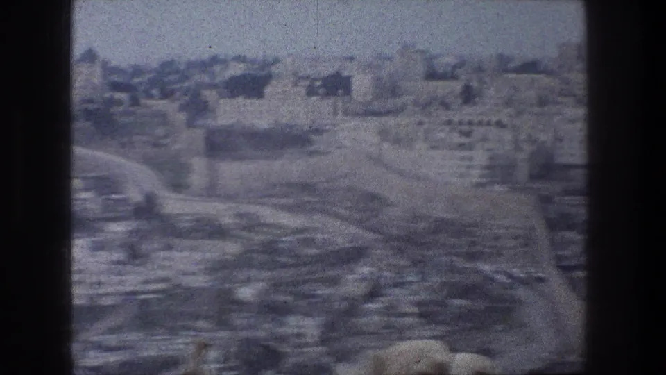 1976 Jerusalem aerial home-movie frame with a road, stone buildings, terraces, and soft motion blur.