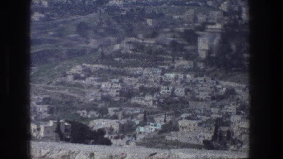 Soft 8mm frame of a Jerusalem hillside view, showing dense buildings, roads, and open barren ground.