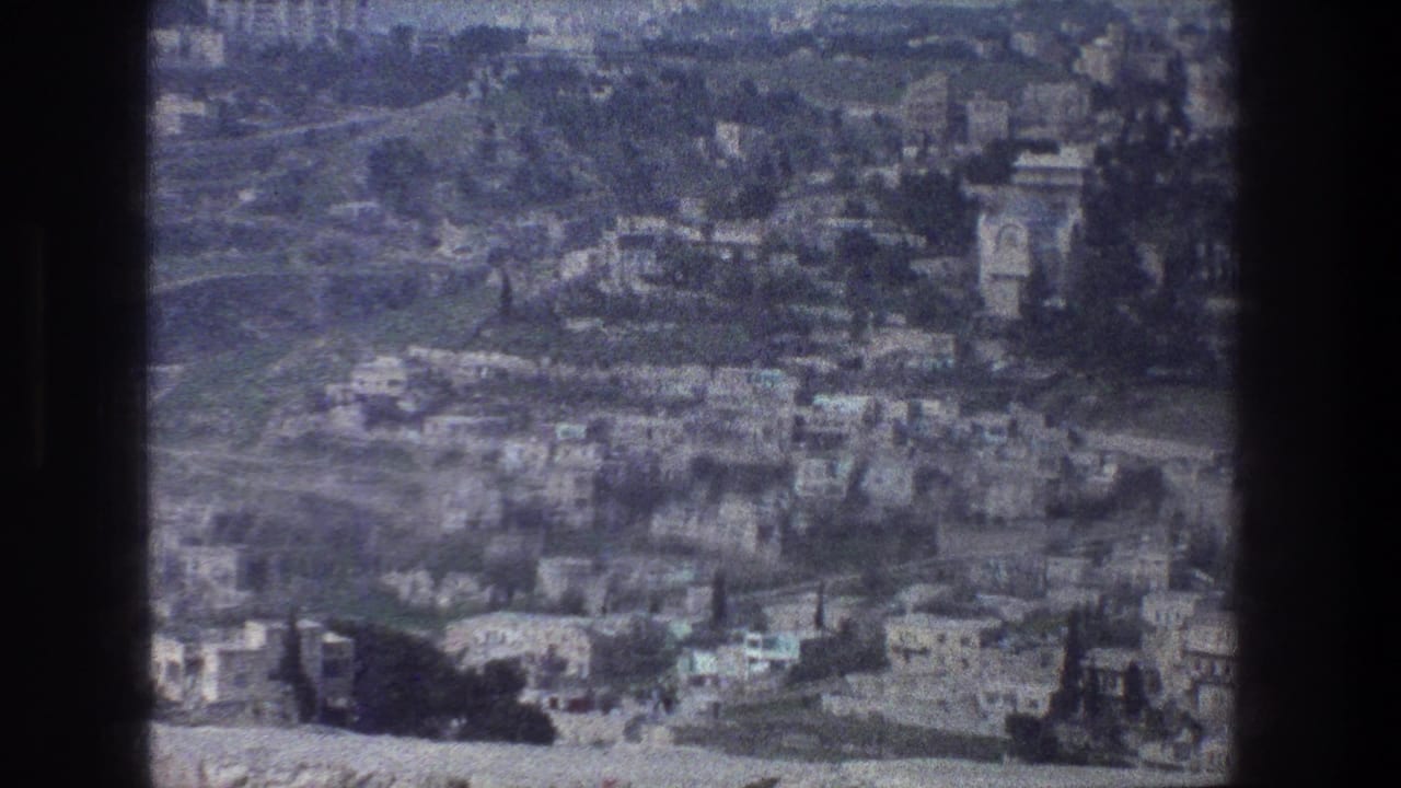 1976 Jerusalem cityscape from above, with clustered stone buildings, curved roads, greenery, and a tower-like landmark shape.