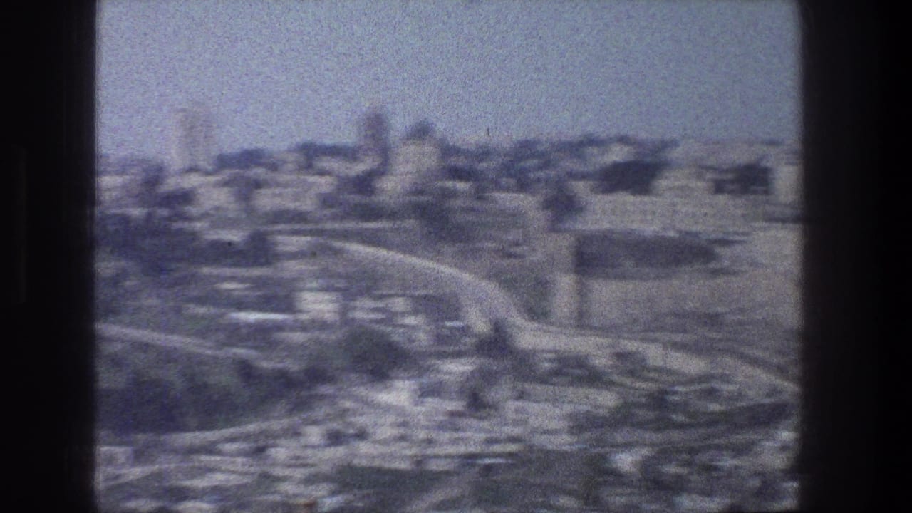 Soft aerial view of dense buildings and curving roads with dark 8mm frame borders.