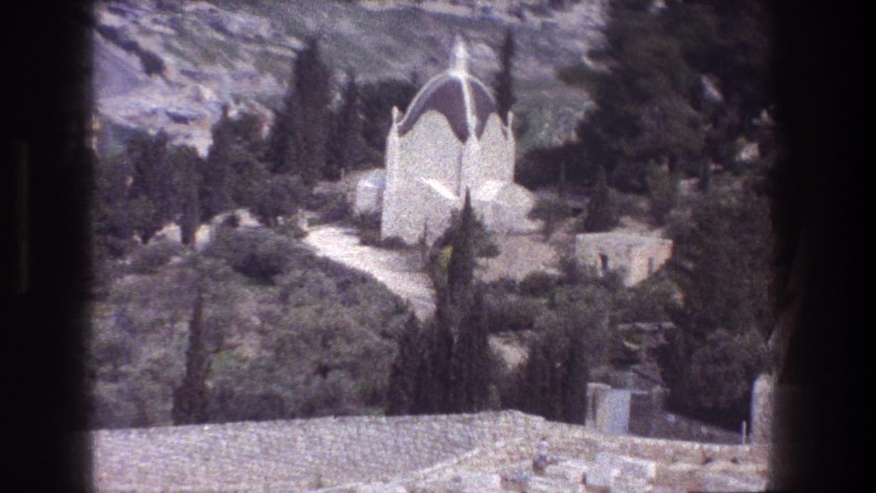 White domed hillside structure with trees, shrubs, and stonework.