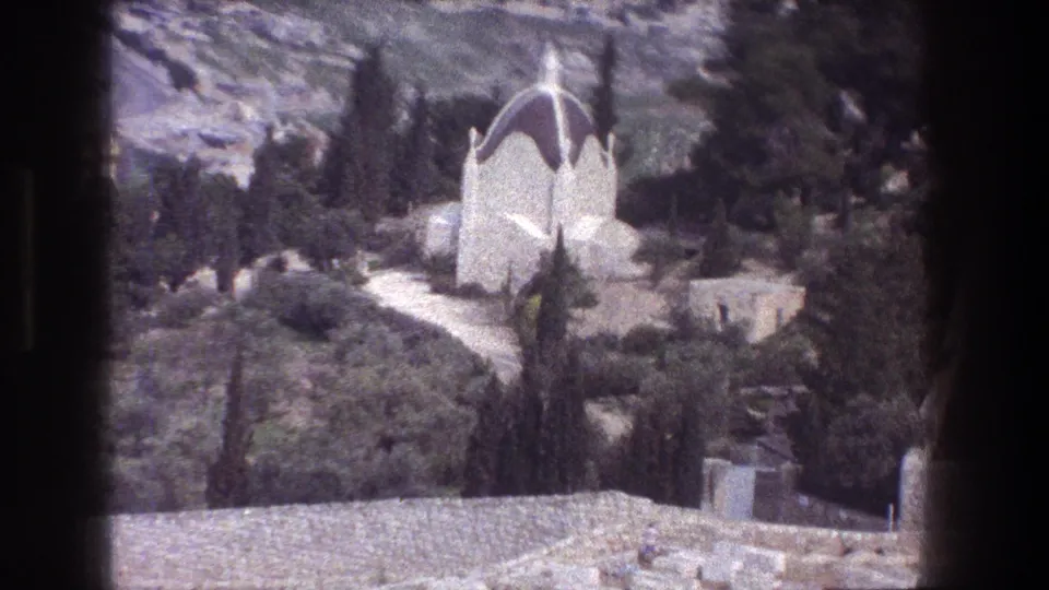 1976 Jerusalem home-movie frame showing a white domed mausoleum-like building on a landscaped hillside with paths and tall trees.
