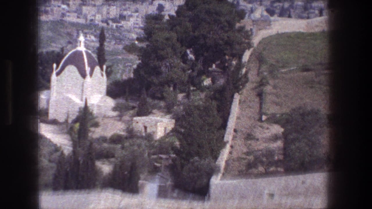 White domed building among trees on a hillside, framed by dark 8mm film edges.