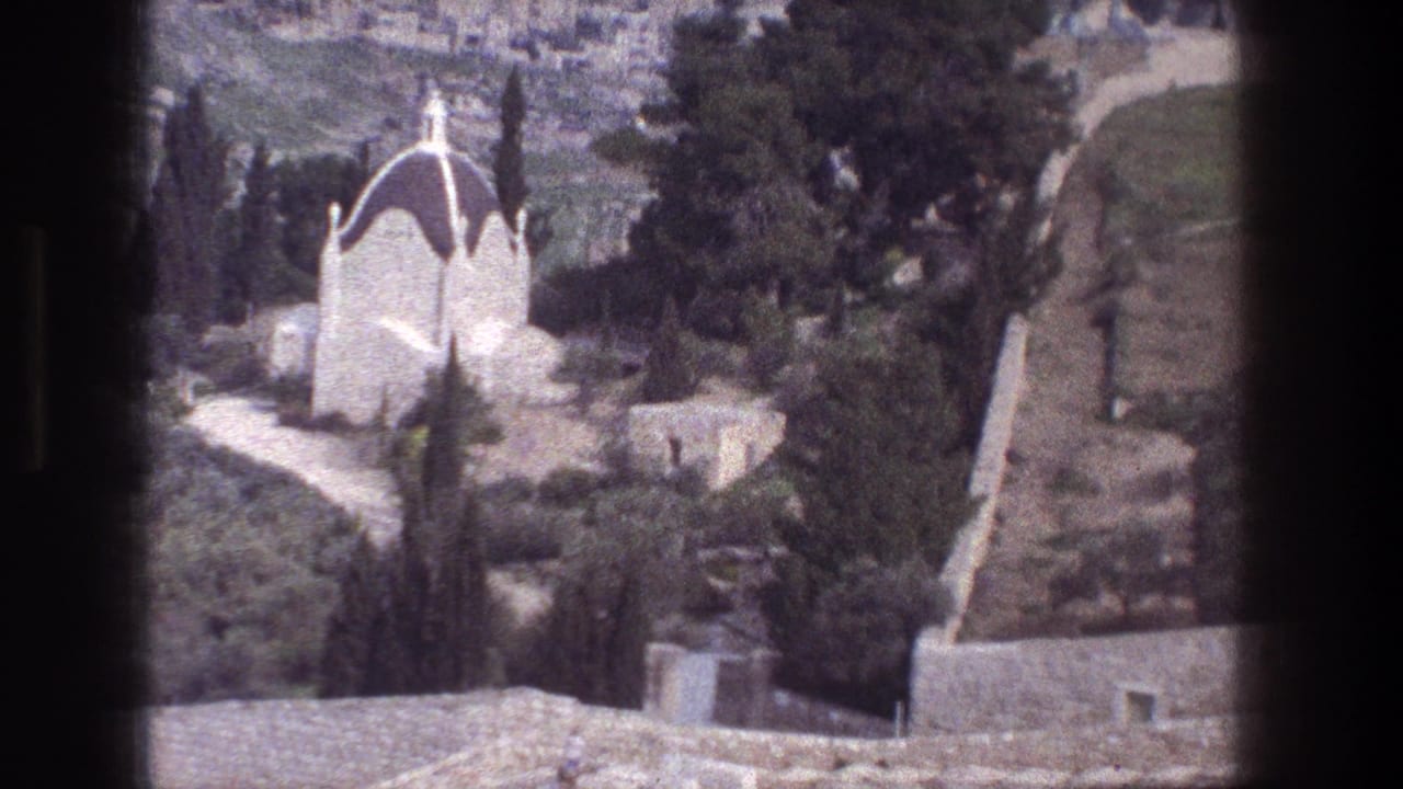 1976 Jerusalem view of a white domed building partly surrounded by trees, with stone paths and film-gate edges visible.