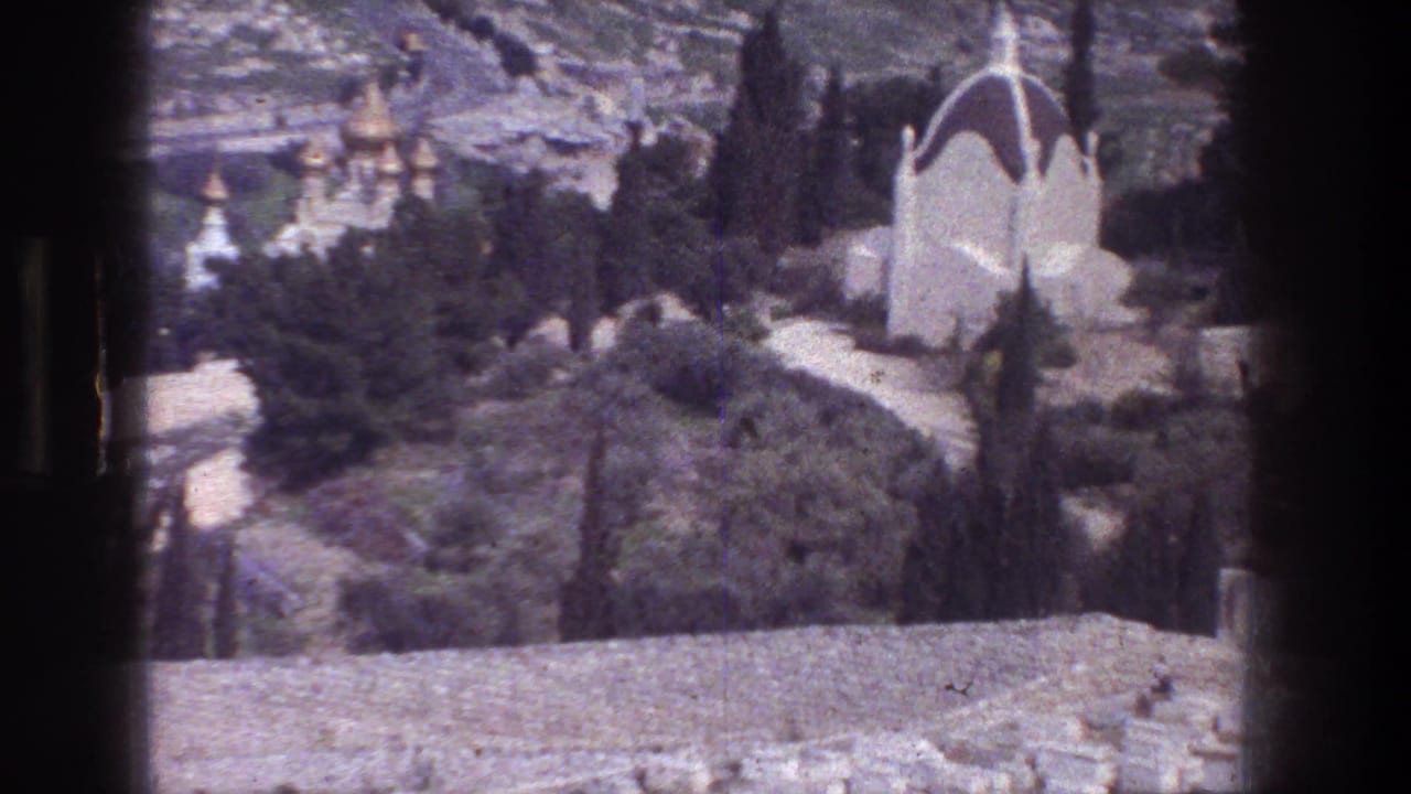 Mount of Olives overlook in Jerusalem with a white chapel at right, trees and paths below, and distant golden onion domes on the hillside.
