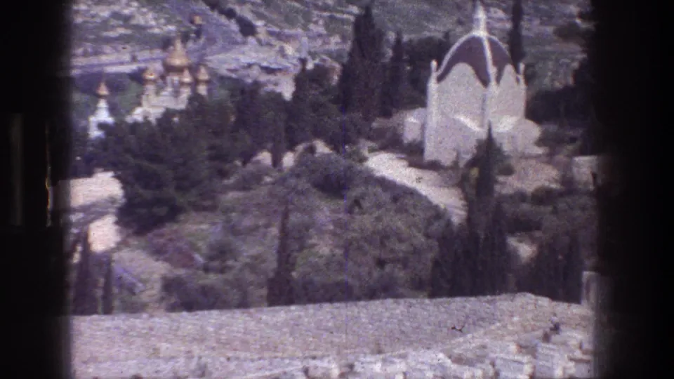 Mount of Olives overlook in Jerusalem with a white chapel at right, trees and paths below, and distant golden onion domes on the hillside.