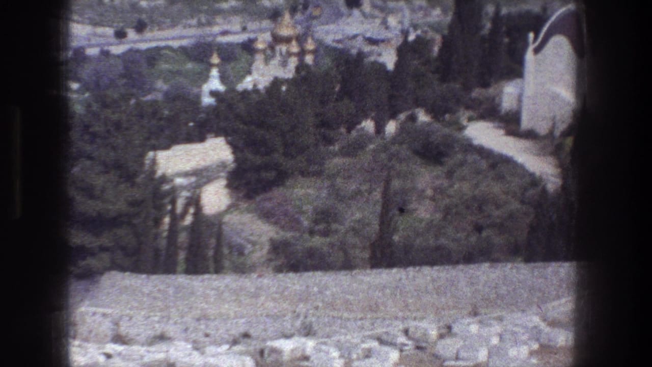 Stone wall foreground with trees, hillside paths, and distant domes beyond.