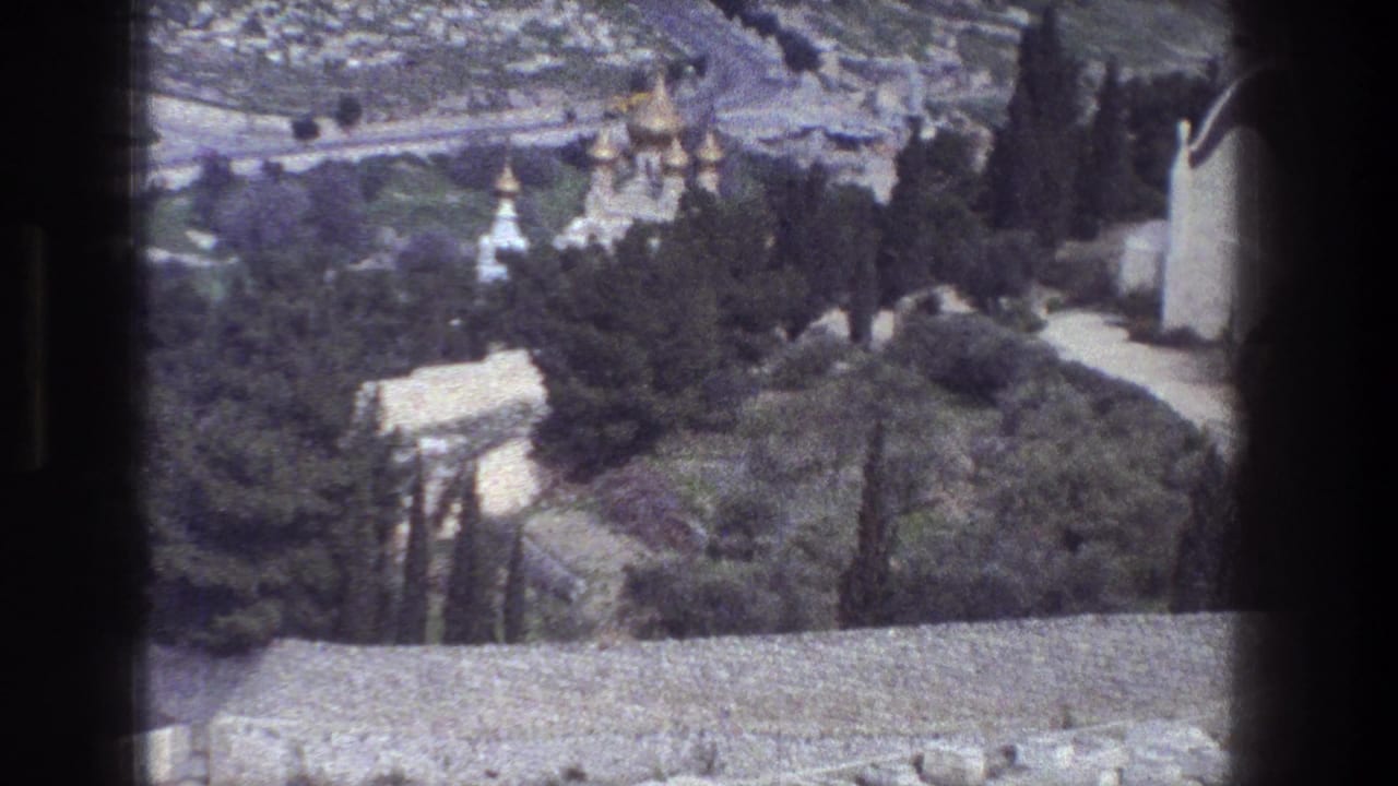 1976 8mm view over Jerusalem trees, domed buildings, white towers and a road seen from an elevated position.