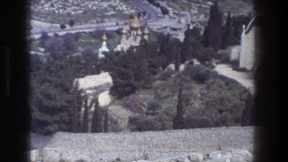1976 8mm view over Jerusalem trees, domed buildings, white towers and a road seen from an elevated position.