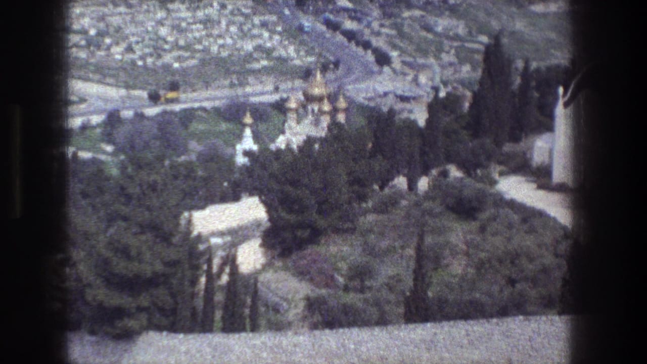 1976 8mm view over Jerusalem with gold church domes among trees and dense city streets in the background.