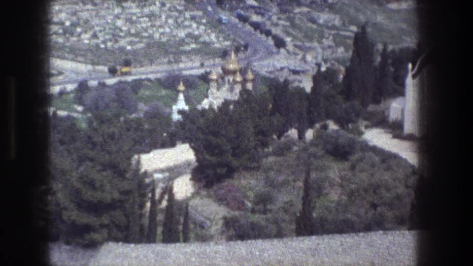 1976 8mm view over Jerusalem with gold church domes among trees and dense city streets in the background.