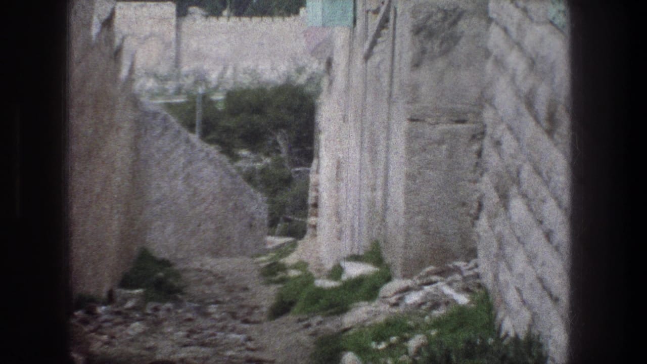 Narrow stone path between weathered walls with greenery and rubble.