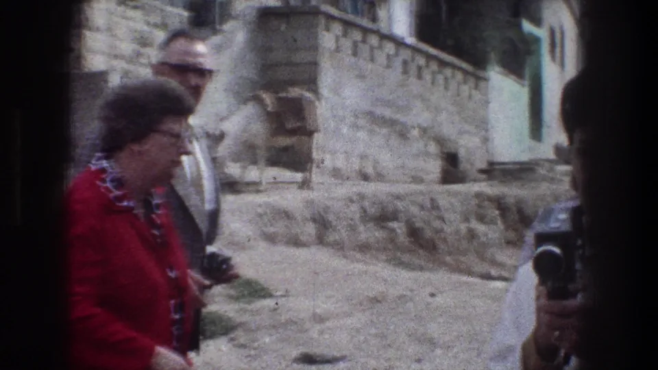 1976 Jerusalem frame showing adults gathered near a donkey on a stone street, with another camera at the right edge.
