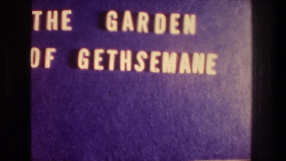 Close 8mm frame of the purple Garden of Gethsemane title card, with the lettering partly cropped by the frame.