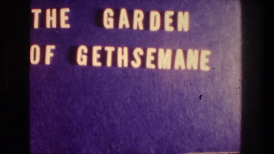 Final 8mm title-card frame reading THE GARDEN OF GETHSEMANE on a purple background with visible film texture.