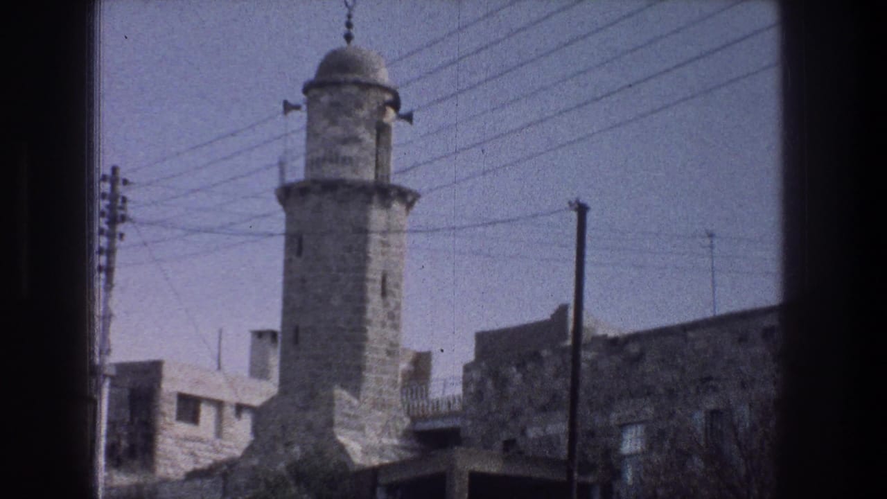 Stone tower with a domed top stands among wires and buildings.