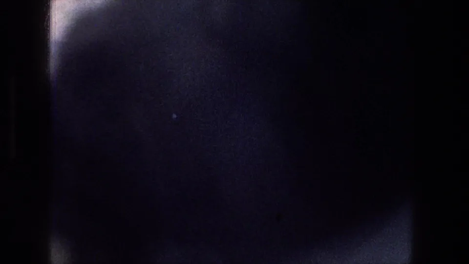 The frame turns mostly dark inside the train-window view, with a partial bright edge and little exterior detail visible.