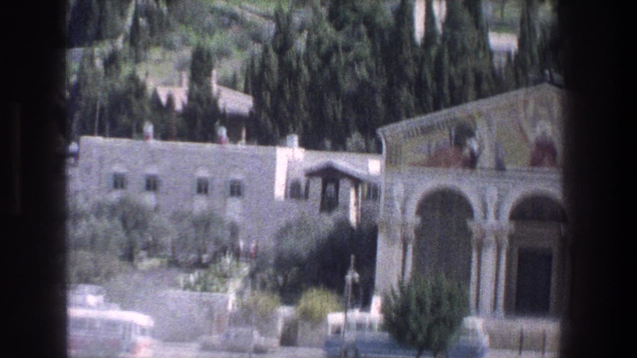 Roadside view of an ornate arched building partly framed by a dark vehicle window.