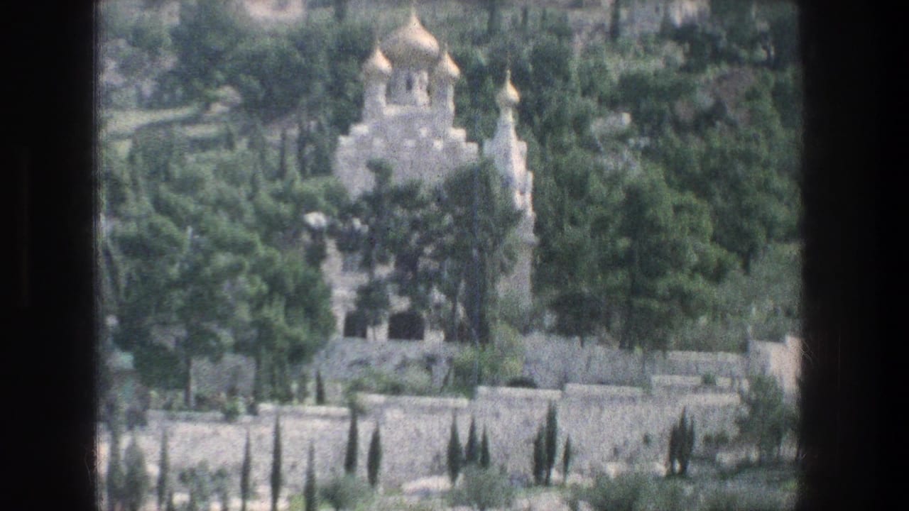 Distant 1976 Jerusalem view of a golden-domed stone church surrounded by greenery, with a long stone wall crossing the foreground.