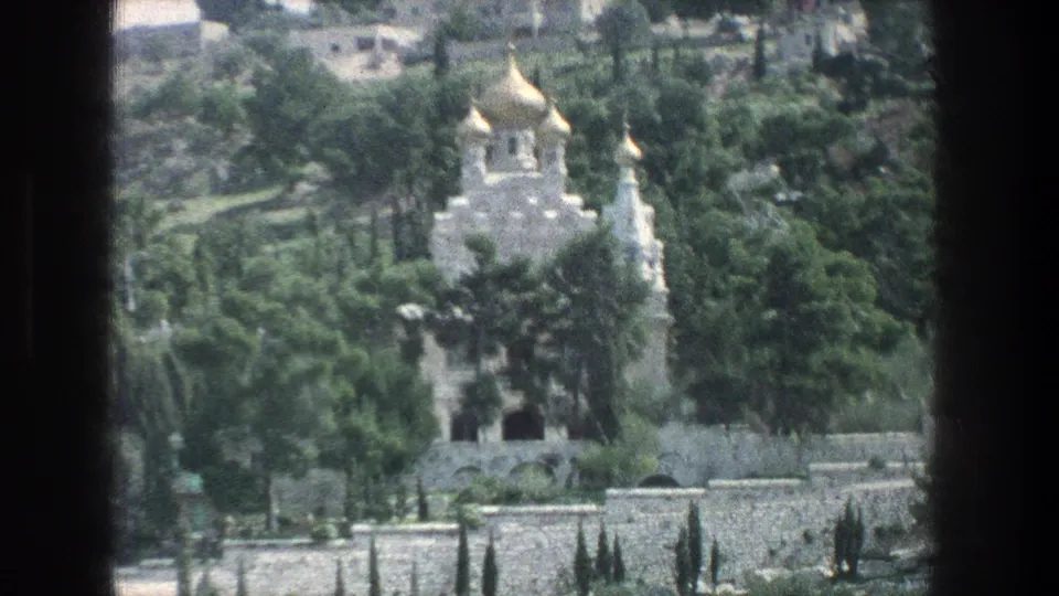 1976 Jerusalem 8mm frame with a closer visitor view of gold domes, white stone architecture, trees, and stone walls.