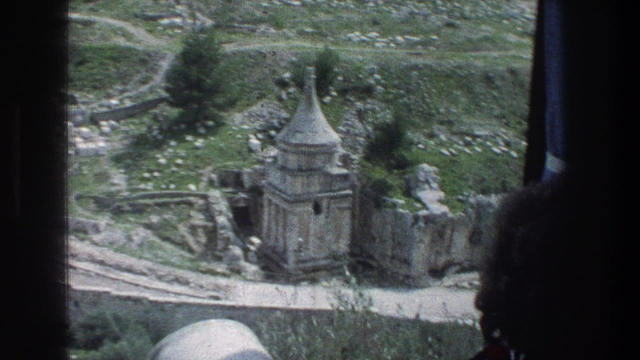 Stone tomb structure with a conical roof seen beyond dark window edges.