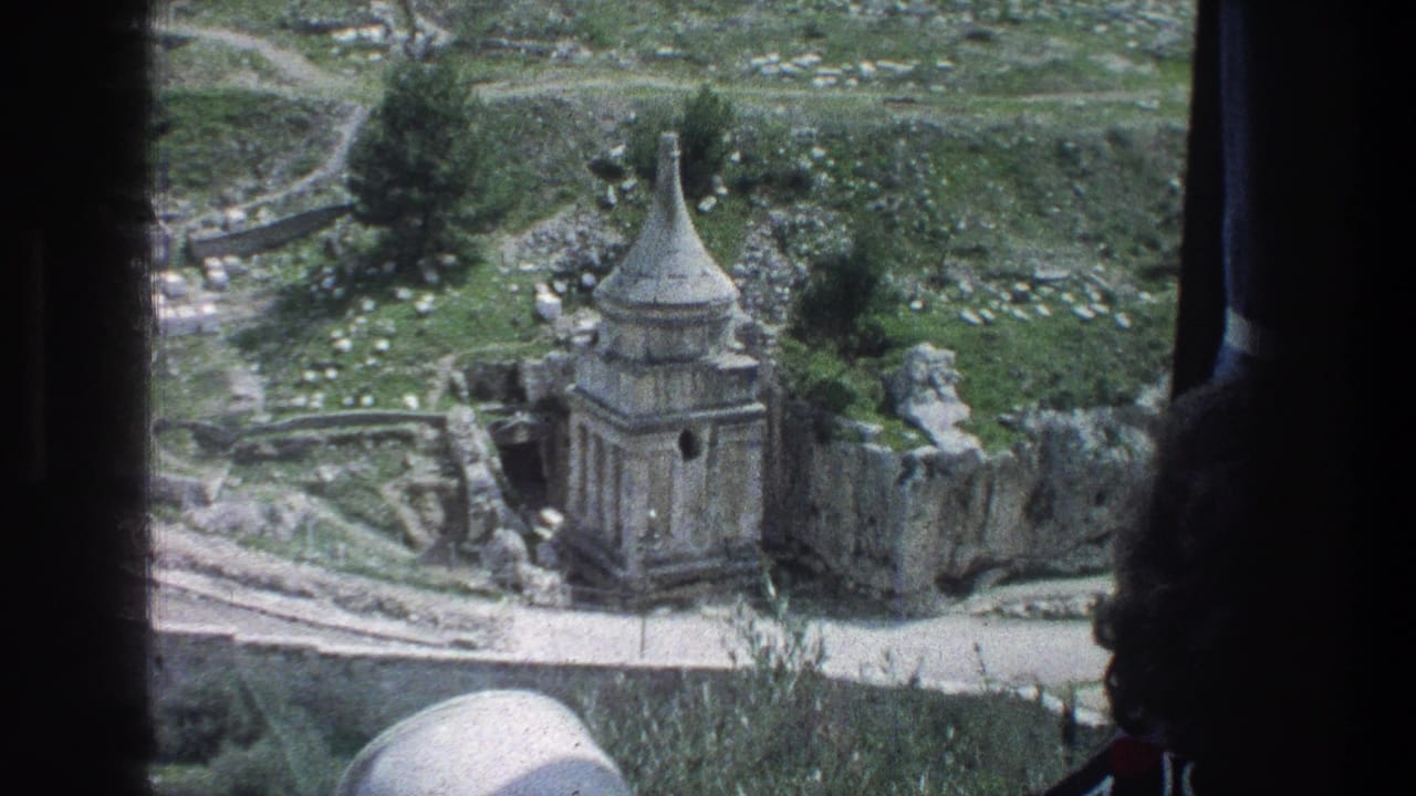 Stone ruin with conical roof seen through a dark vehicle window frame.