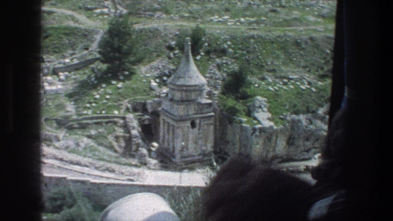 A dark passenger silhouette frames a 1976 Jerusalem view of a stone ruin, paths, grass, and scattered masonry.