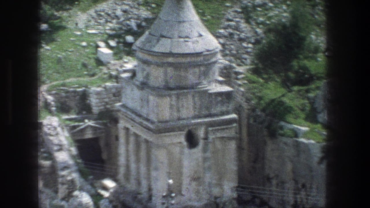 Weathered stone ruin with conical spire on a rocky green hillside.