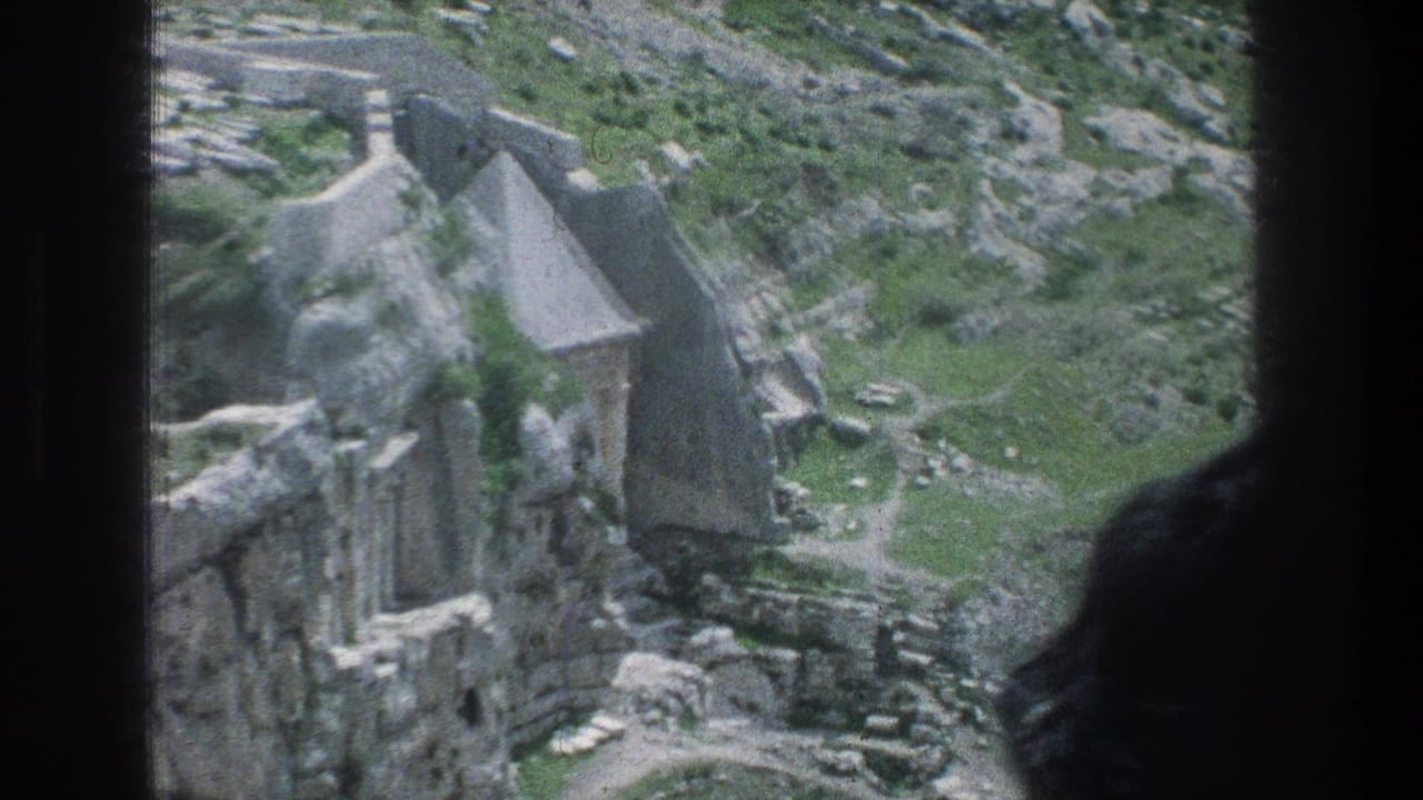 Stone wall ruins and rocky ground framed by a dark vertical edge.