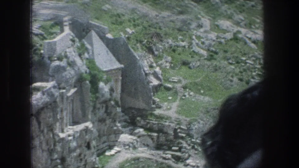 1976 8mm Jerusalem view with slight motion blur, showing stone ruins, uneven rocks, and green vegetation.