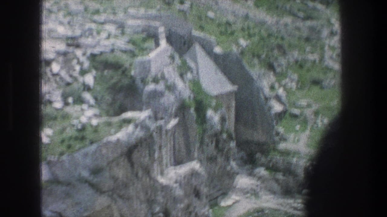 Aerial view of stone ruins and low walls in a rocky green landscape.