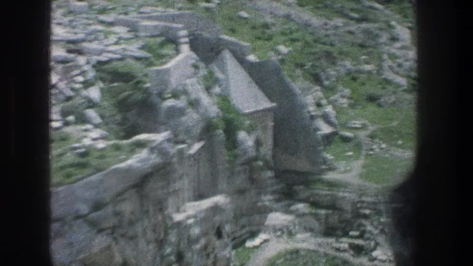 1976 Jerusalem aerial home-movie frame showing stone ruins, green patches, and a dark film edge from the 8mm scan.