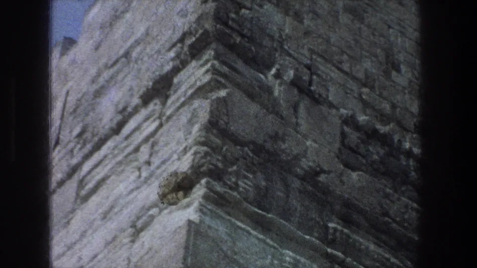 Grainy 8mm close view of rough masonry or wall texture at the Jerusalem site.